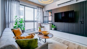 A modern living room with a sofa, a coffee table, a flat-screen TV, and large windows. - w Stunning 2BR w Great Deco in Centriqo (Veracruz)