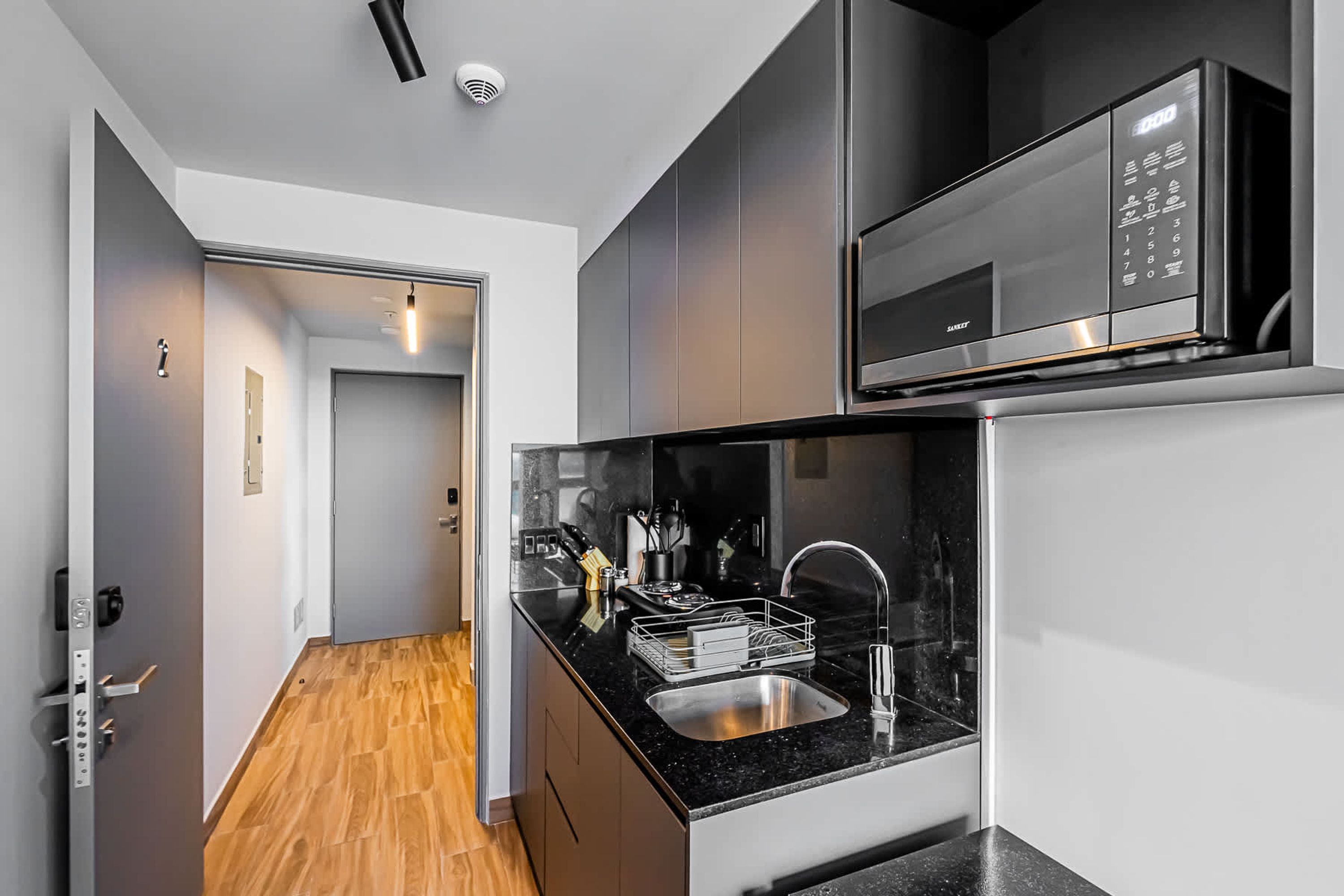 Una cocina moderna con encimera negra, electrodomésticos de acero inoxidable y suelo de madera.