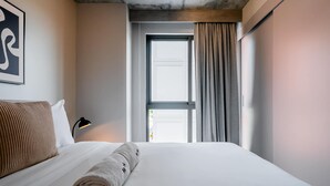 A hotel room with a bed, a window with curtains, a wall-mounted lamp, and a framed picture. - w Stunning 2BR w Great Deco in Centriqo (Veracruz)