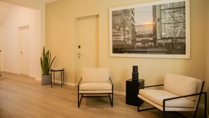 A modern living room with two white armchairs, a large framed picture on the wall, a potted plant, and a small side table. - w Impressive 5BR w Terrace in Miraflores (Lima)