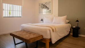 A bedroom with a bed, a bench, a bedside table, a lamp, a picture on the wall, and a window with bars. - w Impressive 5BR w Terrace in Miraflores (Lima)