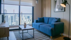 Una sala de estar moderna con un gran ventanal, un sofá azul, una mesa de centro y una lámpara de pie.