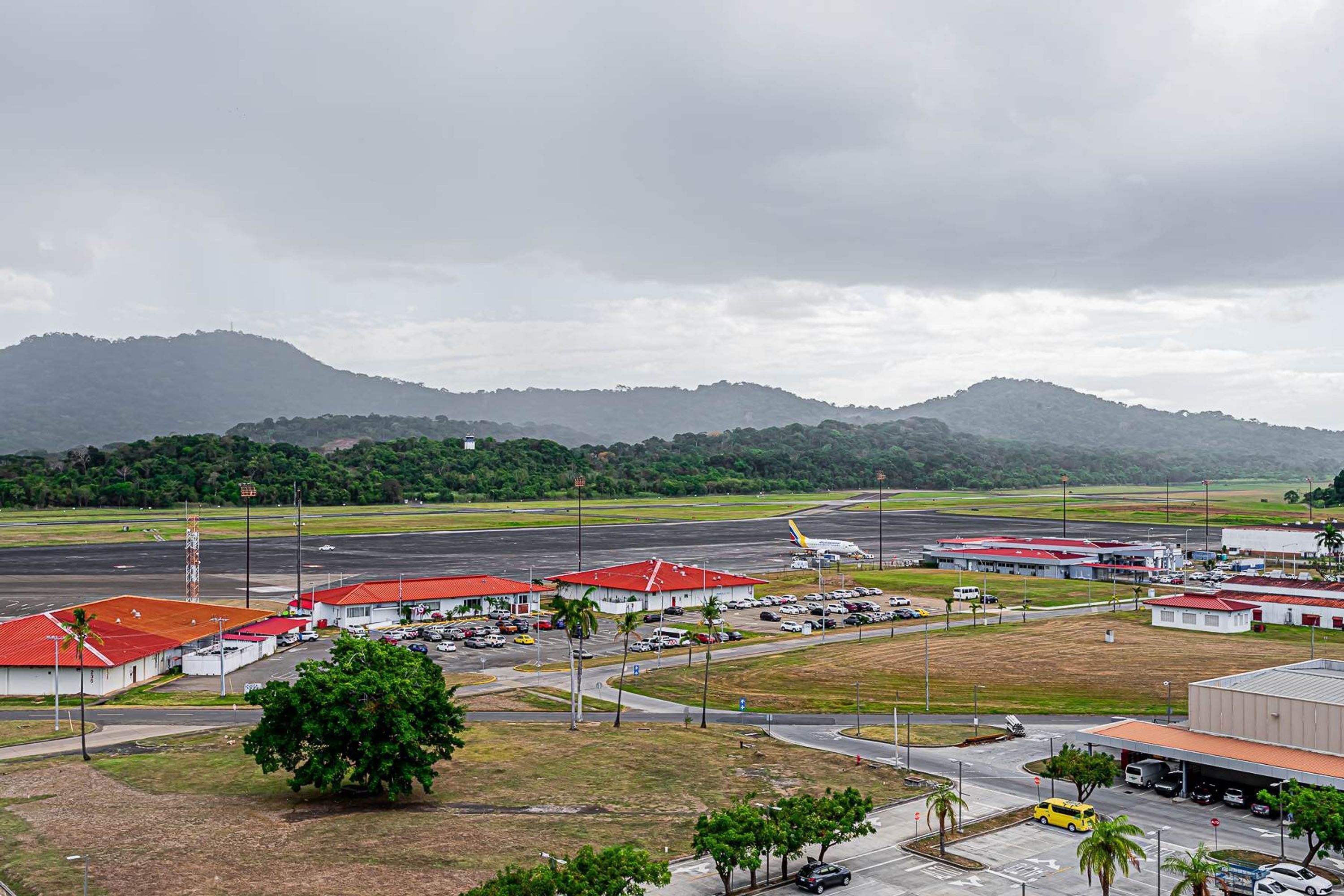 An airport with multiple hangars, a runway, and surrounding greenery.
