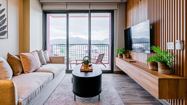 Ein modernes Wohnzimmer mit einer Couch, einem Couchtisch und einem Fernseher an einer Holzwand.