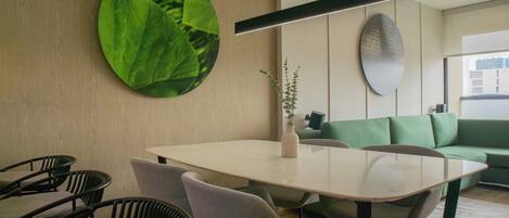 Un espace repas moderne avec une table ronde, des chaises et un canapé vert.