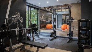 Une salle de sport équipée de matériel de musculation, d’un banc et de ballons d’exercice.