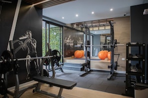 A gym with weightlifting equipment, a bench, and exercise balls.