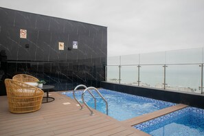 A rooftop pool with a view of the sea, a wicker chair, and a small table. - w Distinctive 1BR w Balcony in Barranco (Lima)