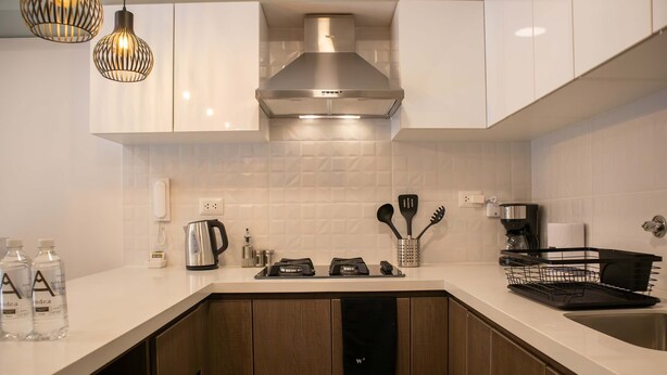 A modern kitchen with white cabinetry, a stainless steel range hood, and a built-in dishwasher. - w Stunning 1BR in Miraflores (Lima)