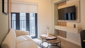 A modern living room with a sofa, a round coffee table, and a TV mounted on the wall. - w Stunning 1BR in Miraflores (Lima)