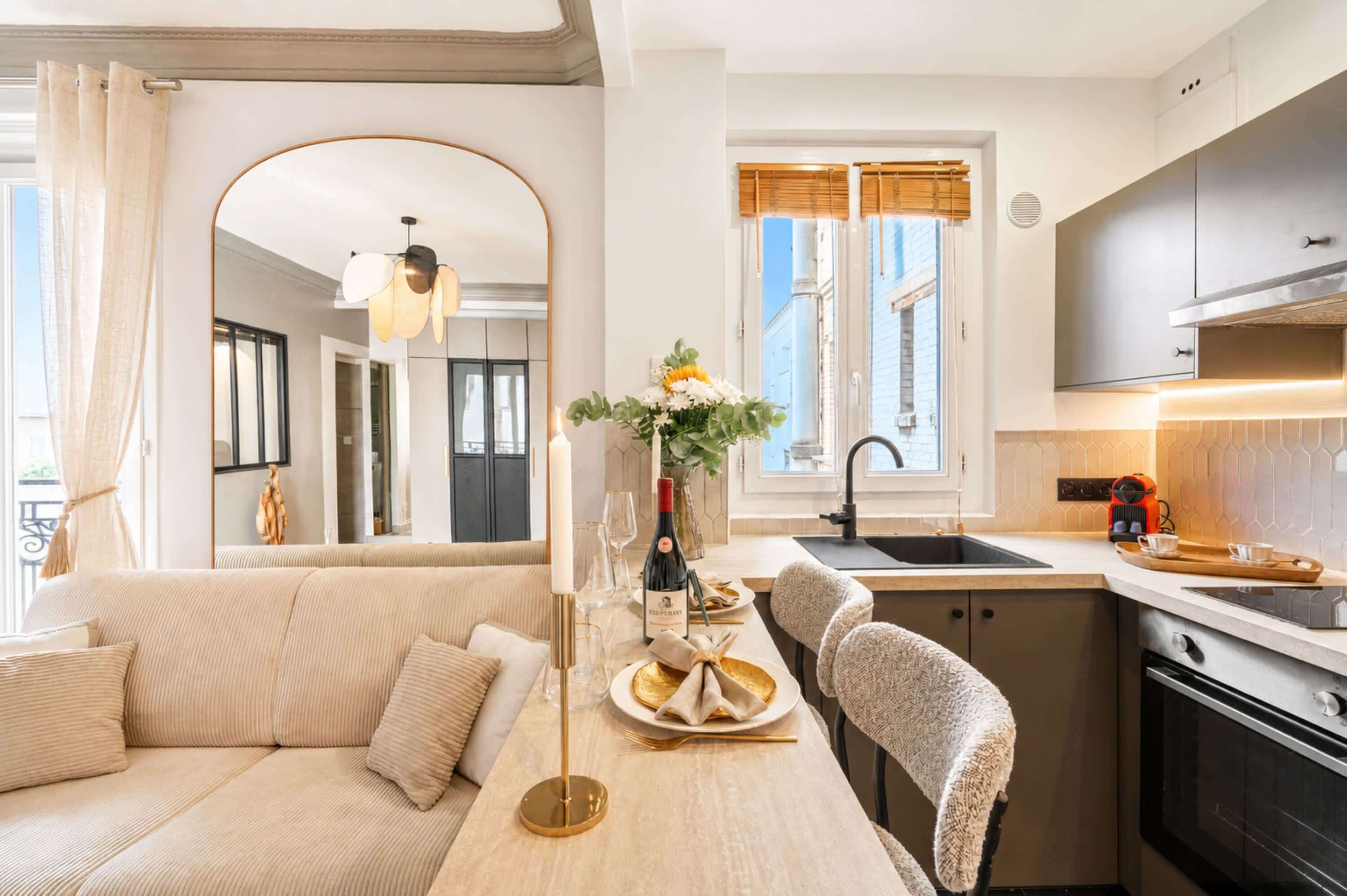 Eine moderne Küche mit Kochinsel, ein Essbereich mit einer Couch und Blick auf die Stadt durch große Fenster.