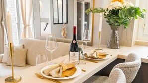 A dining table set with plates, glasses, a bottle of wine, and a vase of flowers. - Elegant apartment with lift - Gare de Lyon & Bercy (Paris)