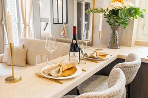 A dining table set with plates, glasses, a bottle of wine, and a vase of flowers. - Elegant apartment with lift - Gare de Lyon & Bercy (Paris)