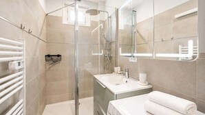 A modern bathroom with a glass shower enclosure, a white sink, and a large mirror. - Elegant apartment with lift - Gare de Lyon & Bercy (Paris)