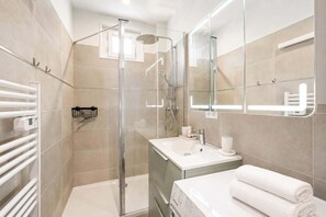 A modern bathroom with a glass shower enclosure, a white sink, and a large mirror. - Elegant apartment with lift - Gare de Lyon & Bercy (Paris)