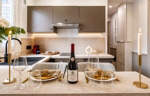 Una cocina moderna con una botella de vino, copas y una vela sobre la encimera.