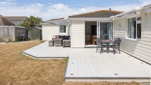 Een gelijkvloerse stacaravan met een overdekte patio, een klein zitgedeelte buiten en een omheinde achtertuin.