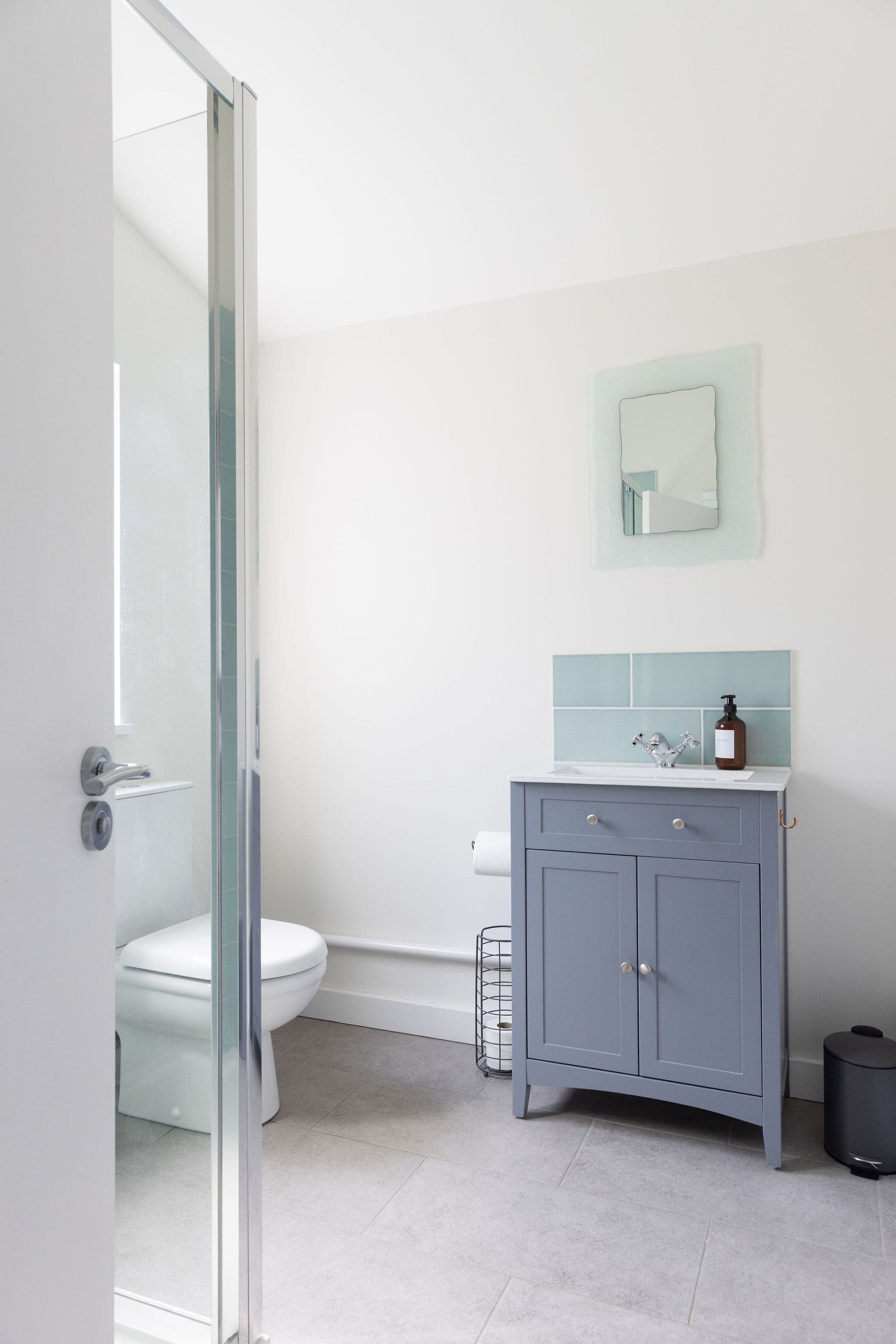 Ein Badezimmer mit Toilette, einem Schrank, einem Spiegel und einer Duschkabine.