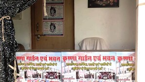 A hotel reception area with informational posters in a local language, a door, and a framed picture on the wall. - Krishan Bhavan And Events (Nagaur)