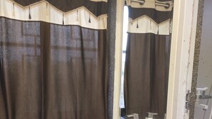 A bathroom with a white sink, dark brown curtains, and a mirror. - Krishan Bhavan And Events (Nagaur)