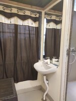 Un baño con lavamanos blanco, un espejo y cortina de ducha.
