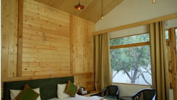 A wooden room with a bed, two chairs, and a window with curtains. - Nine Apple Resort Dharali Harsil (Bhatwari)