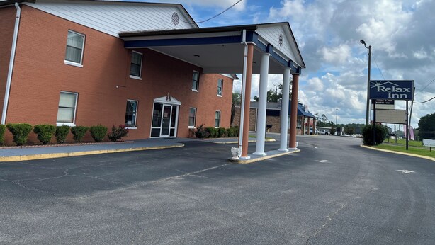 A brick building with a covered entrance and a sign for a Relax Inn.