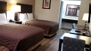 A hotel room with two beds, a desk, and a chair.