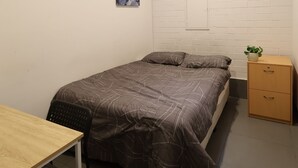 A small, modern bedroom with a bed, a desk, and a nightstand. - Quokka Backpackers Hostel Perth - note - Valid passport required to check in (WA)