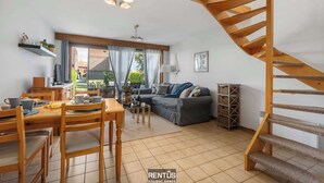 A spacious living area with a dining table, sofa, and a wooden staircase.