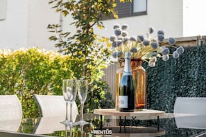 A table with two wine glasses, a bottle of wine, and a vase with flowers.