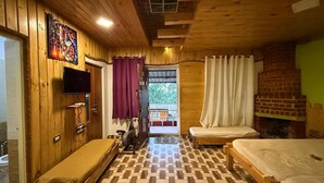 A wooden-themed room with two beds, a TV, a fireplace, and a view of the outdoors. - Misty 7-Bedroom Hill Retreat in Kodaikanal–Perfect for groups & Artists (Kodaikanal)