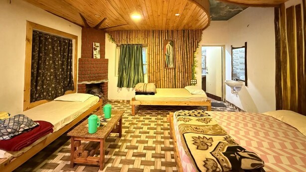 A cozy room with two beds, a small table, and a bench. - Misty 7-Bedroom Hill Retreat in Kodaikanal–Perfect for groups & Artists (Kodaikanal)