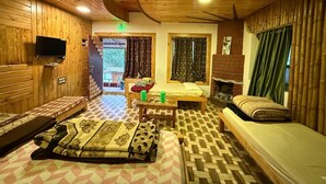 A wooden interior with a sofa, a bed, a table, and a TV. - Misty 7-Bedroom Hill Retreat in Kodaikanal–Perfect for groups & Artists (Kodaikanal)