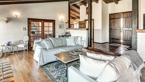 Uma sala de estar espaçosa com um sofá branco, uma mesa de centro e um tapete estampado.