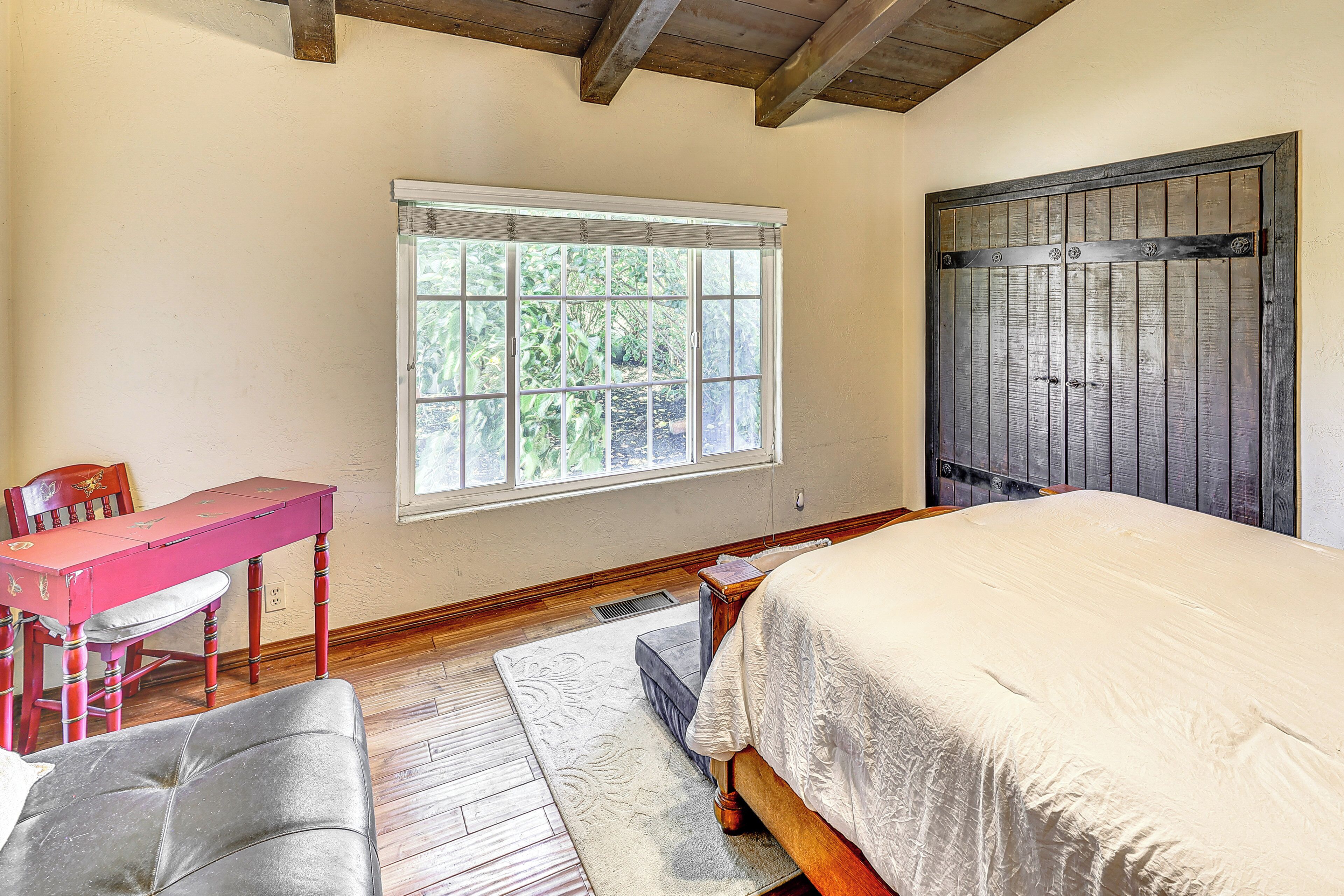 A bedroom with a bed, a desk, and a chair.