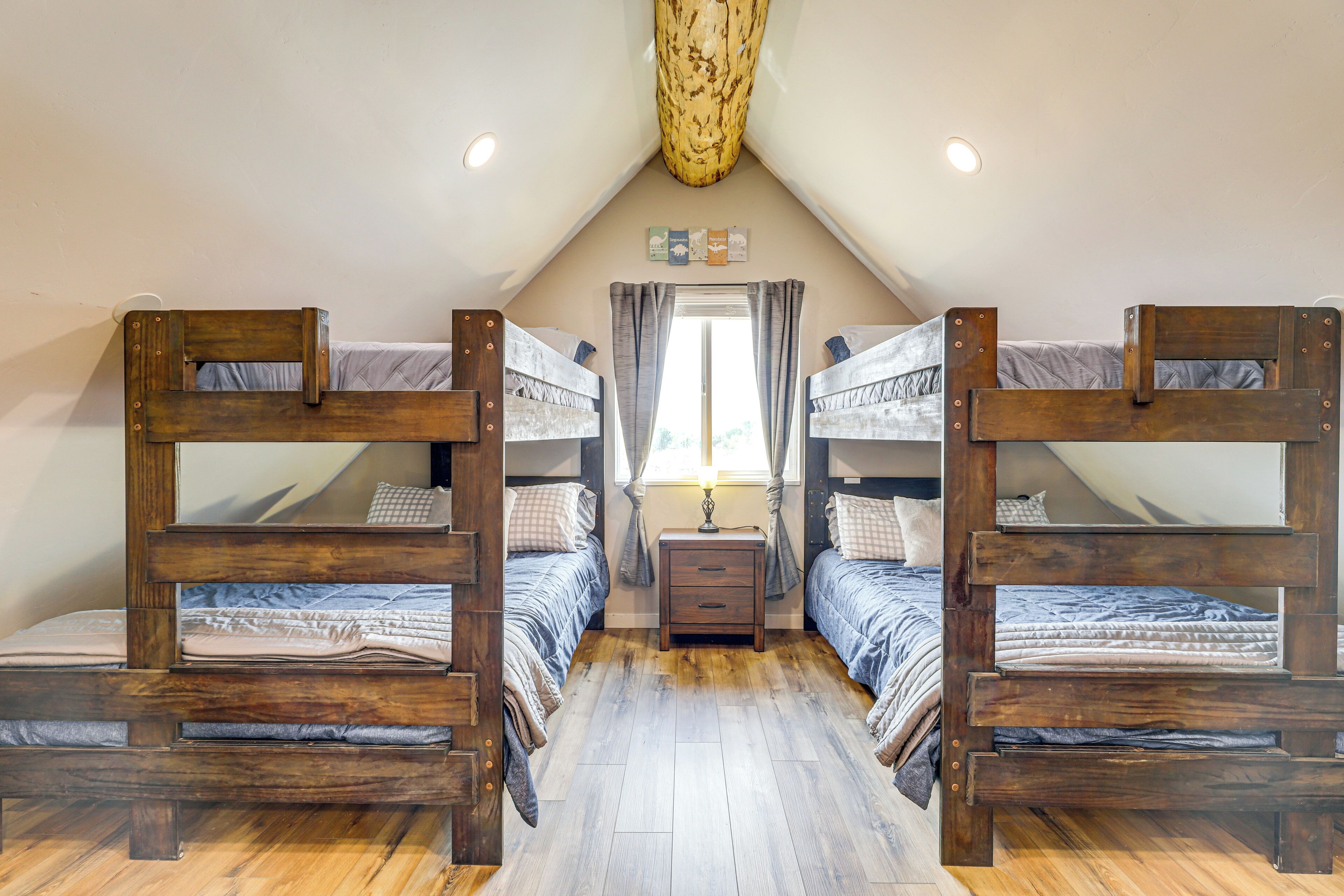 Une chambre avec deux lits superposés, une petite table de chevet avec une lampe et une fenêtre avec des rideaux.