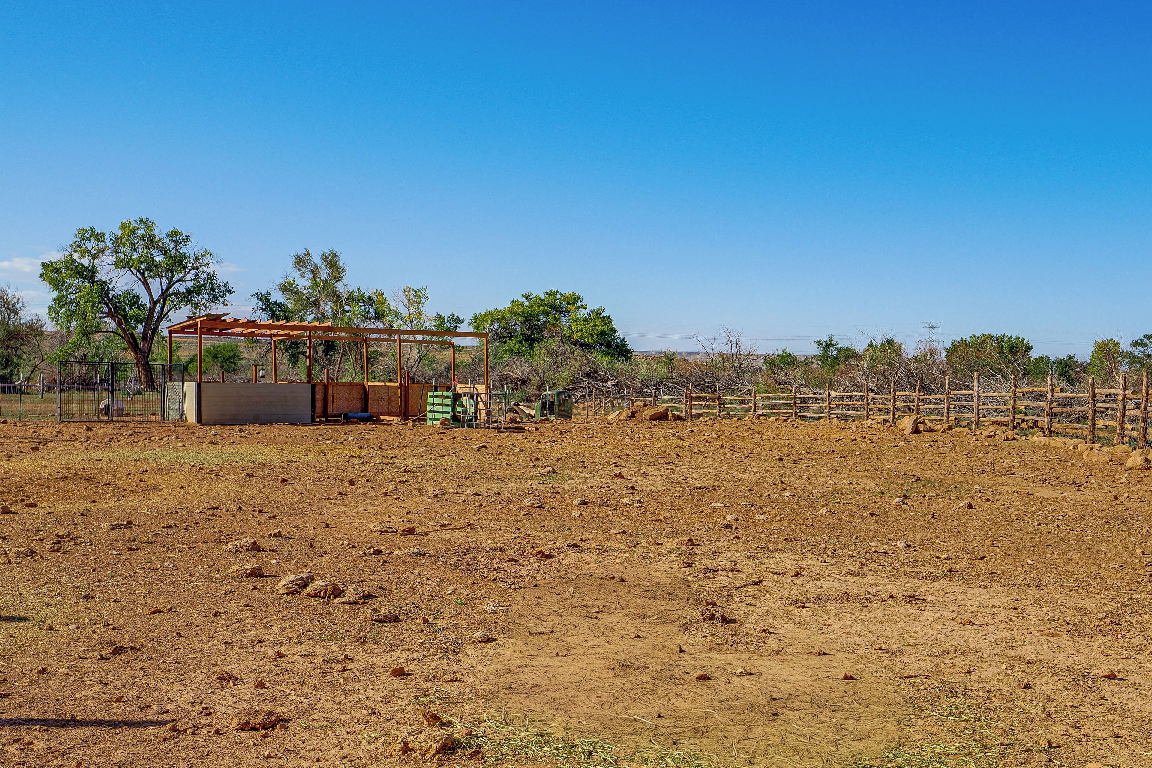 A fenced outdoor area with a small building, possibly a barn or storage shed, and a tree.