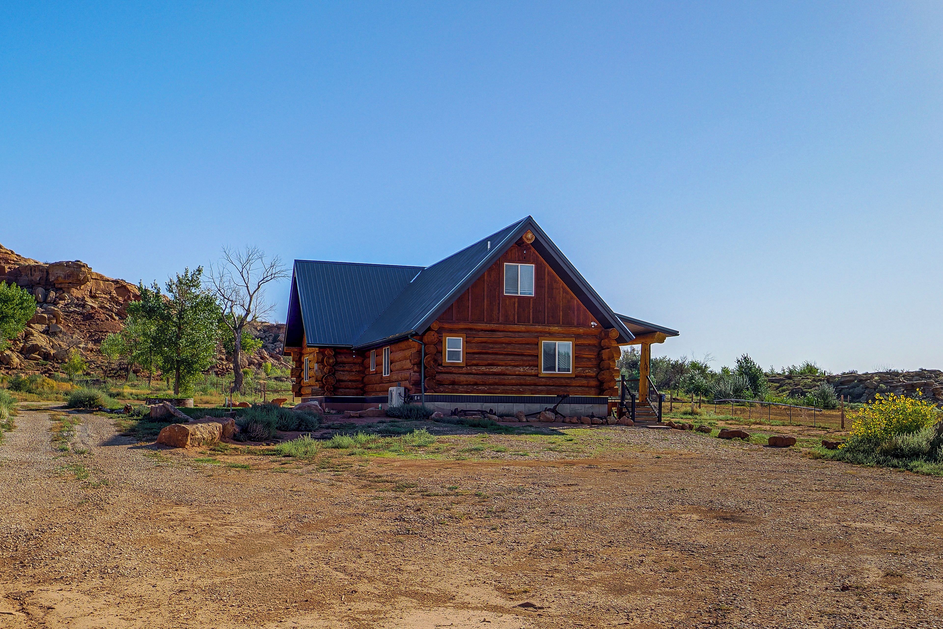 A wooden cabin with a sloped roof, situated in a dry, rocky terrain with sparse vegetation.