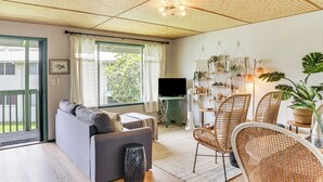 Een gezellige woonkamer met een bank, stoelen, een televisie en een eethoek met een tafel en stoelen.