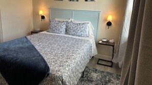 A hotel room with a bed, two bedside tables, a lamp, and three wall-mounted pictures.