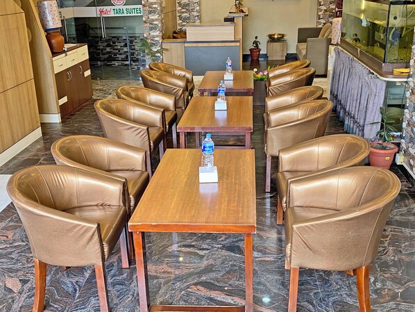 Un hall de hotel con sillones y mesas de cuero, una recepción y un acuario.