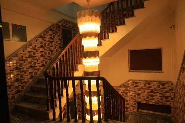 A staircase with a wooden railing and a mosaic-tiled wall. - Hotel Tara Suites (Kathmandu)