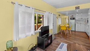 A compact living space with a dining area, kitchenette, and a TV.