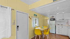 A compact kitchen with a dining area, featuring a white refrigerator, a microwave, and a small stove.