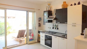 A modern kitchen with a sliding glass door leading to an outdoor area, a built-in oven, and a gas stove. - Casa Libezia A: A welcoming apartment located right on the beach, with Free WI-FI. (Augusta)