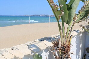 Een strand met een witte muur en een bananenplant op de voorgrond.