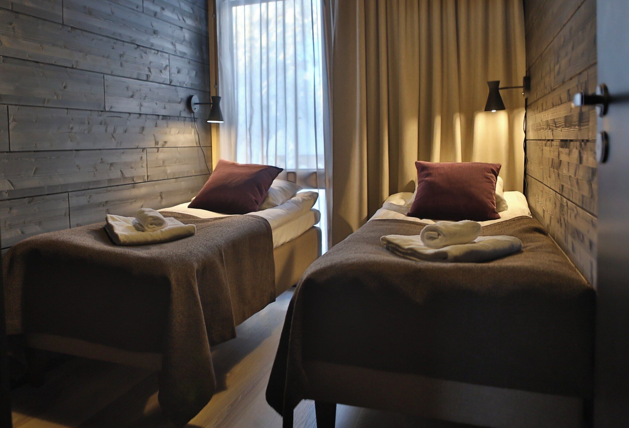A hotel room with two beds, each with a pillow and a towel.