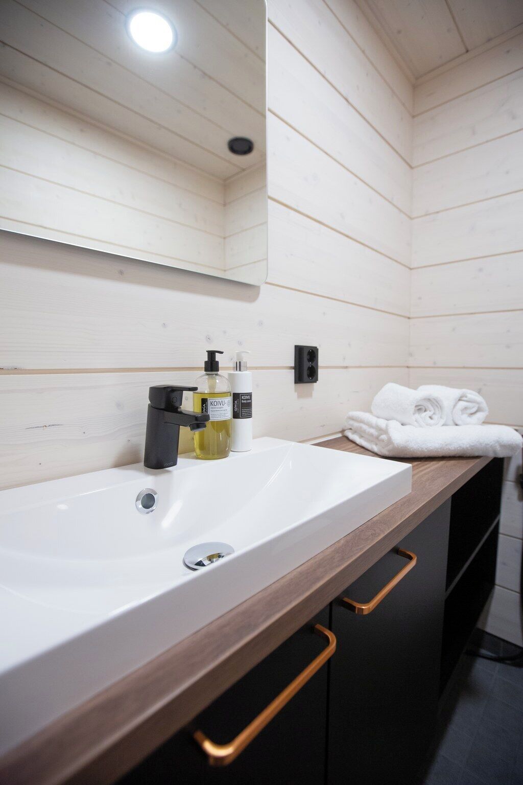 A bathroom with a white sink, wooden countertop, and a towel rack.