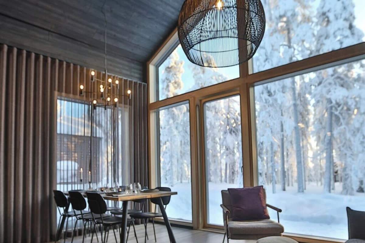 A cozy room with a large window, a dining area, and a seating area with a table and candles.